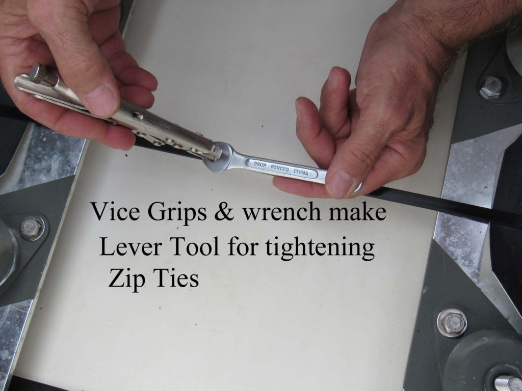 The wrench sits on top of the zip tie "box".  The vice grips are clamped onto the shortened (cut off) end of the tie after being tightened by hand.  Closing the tools similarly to a pair of pliers does the trick.